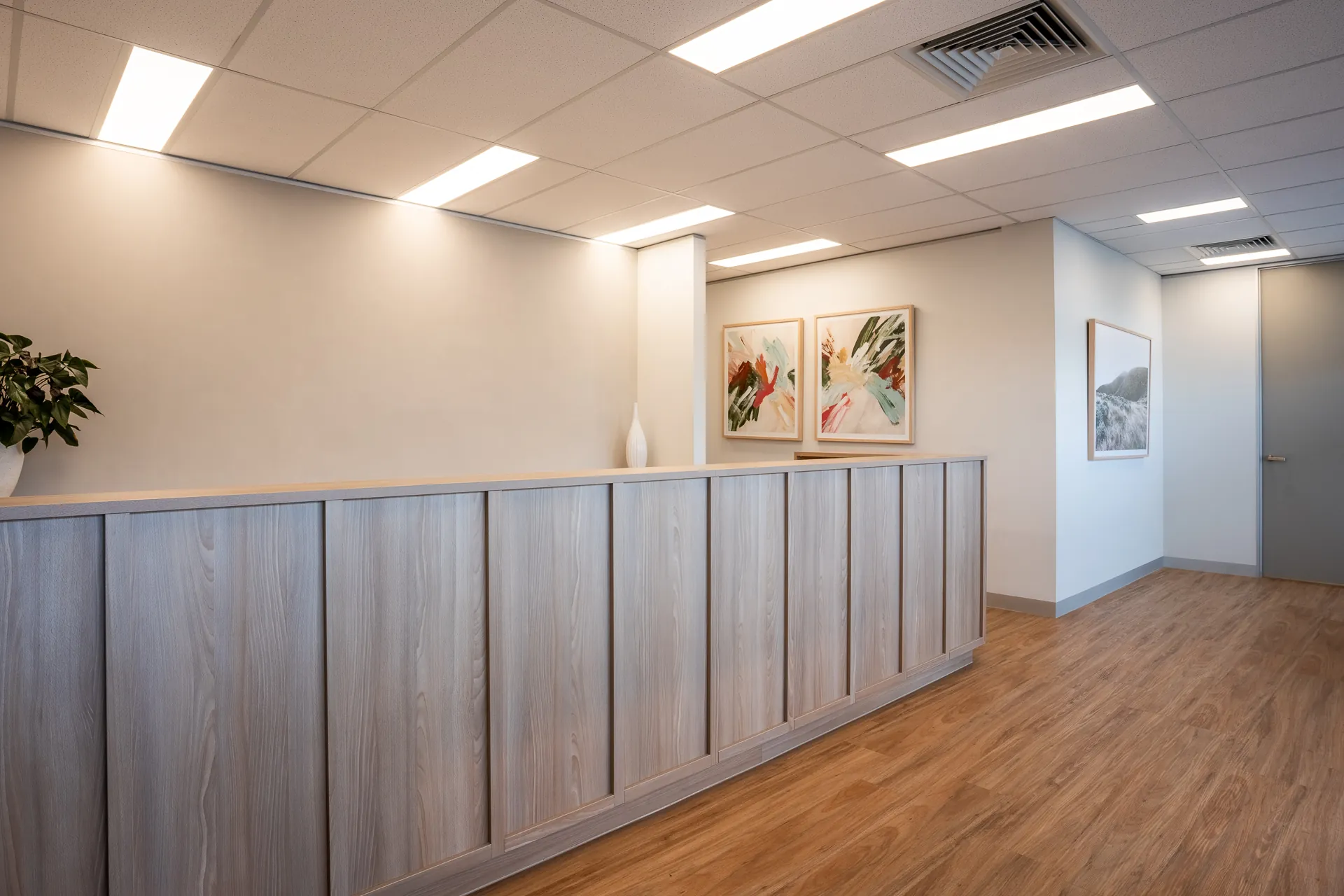 Timber-look reception counter with framed artwork on the wall behind