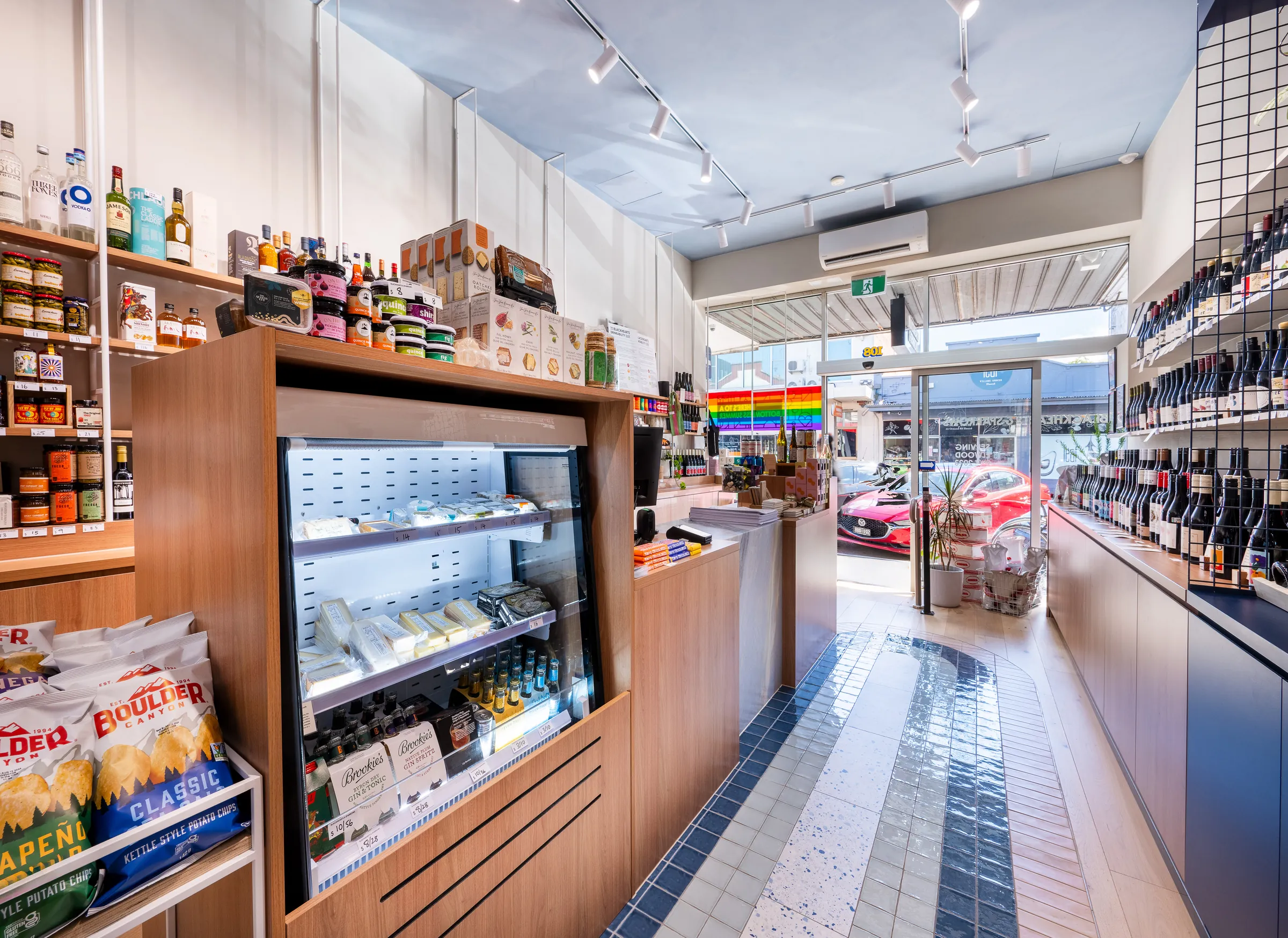 Timber counter and cheese fridge beside the tiled floor path leading to the shopfront