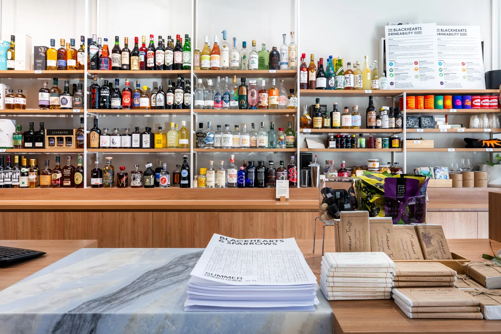 Stone-topped service counter in front of timber and white steel shelving stocked with wine and spirits