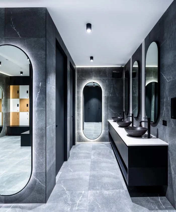 Change room vanity with arched mirrors, dark stone and black joinery