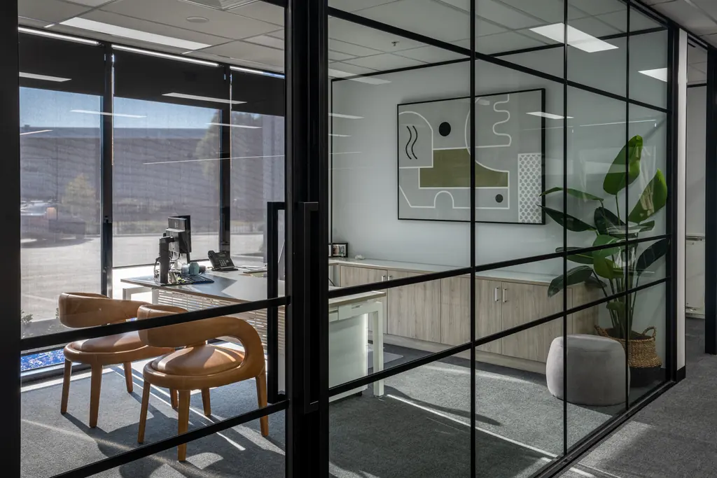 Black-framed glazed offices with timber desks and planting
