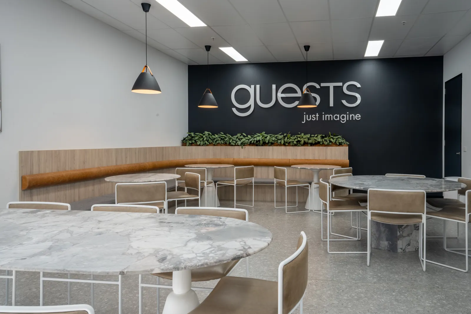 Staff dining area with round stone-topped tables and banquette seating