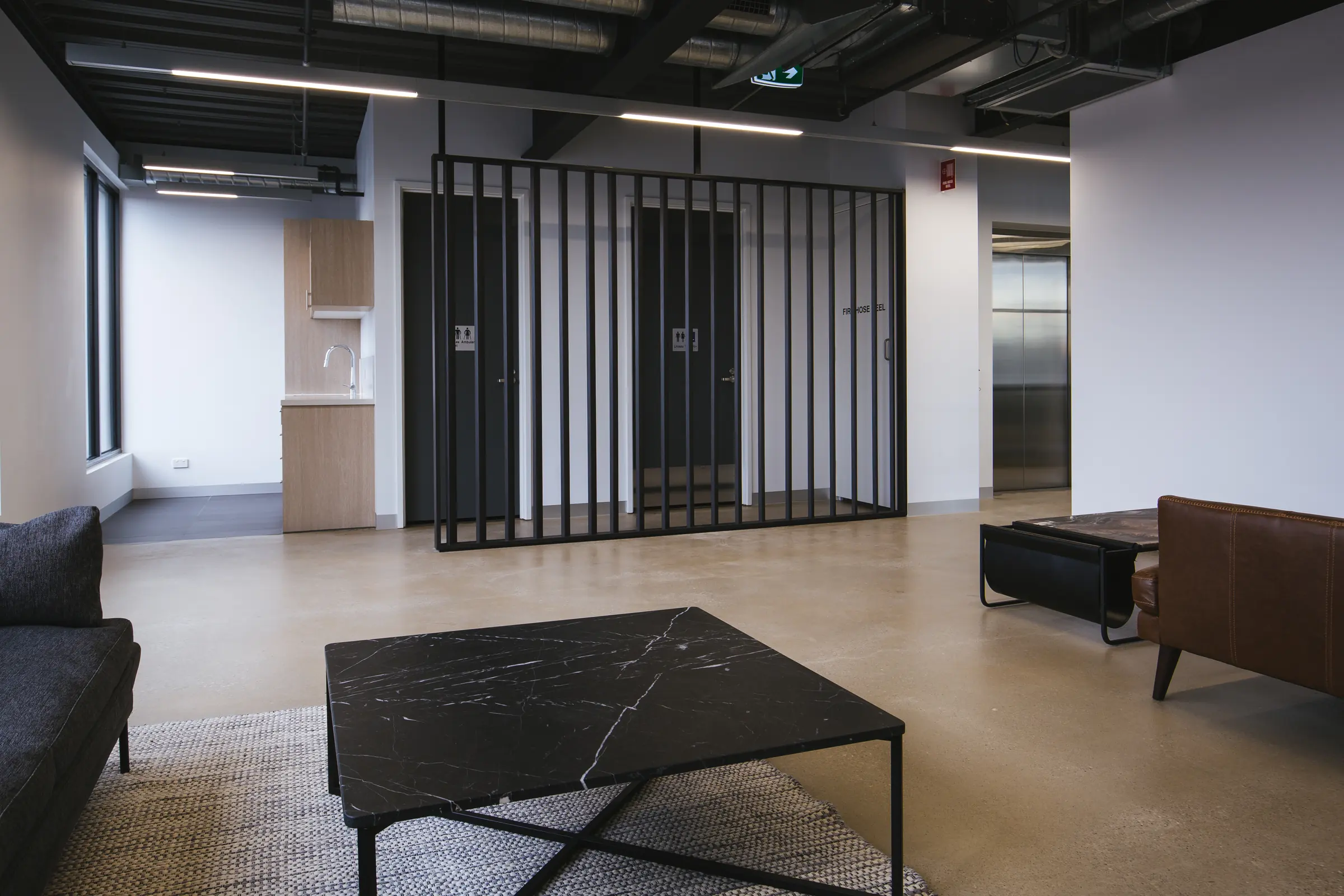 Breakout lounge with a slatted steel screen, leather sofa and stone coffee table