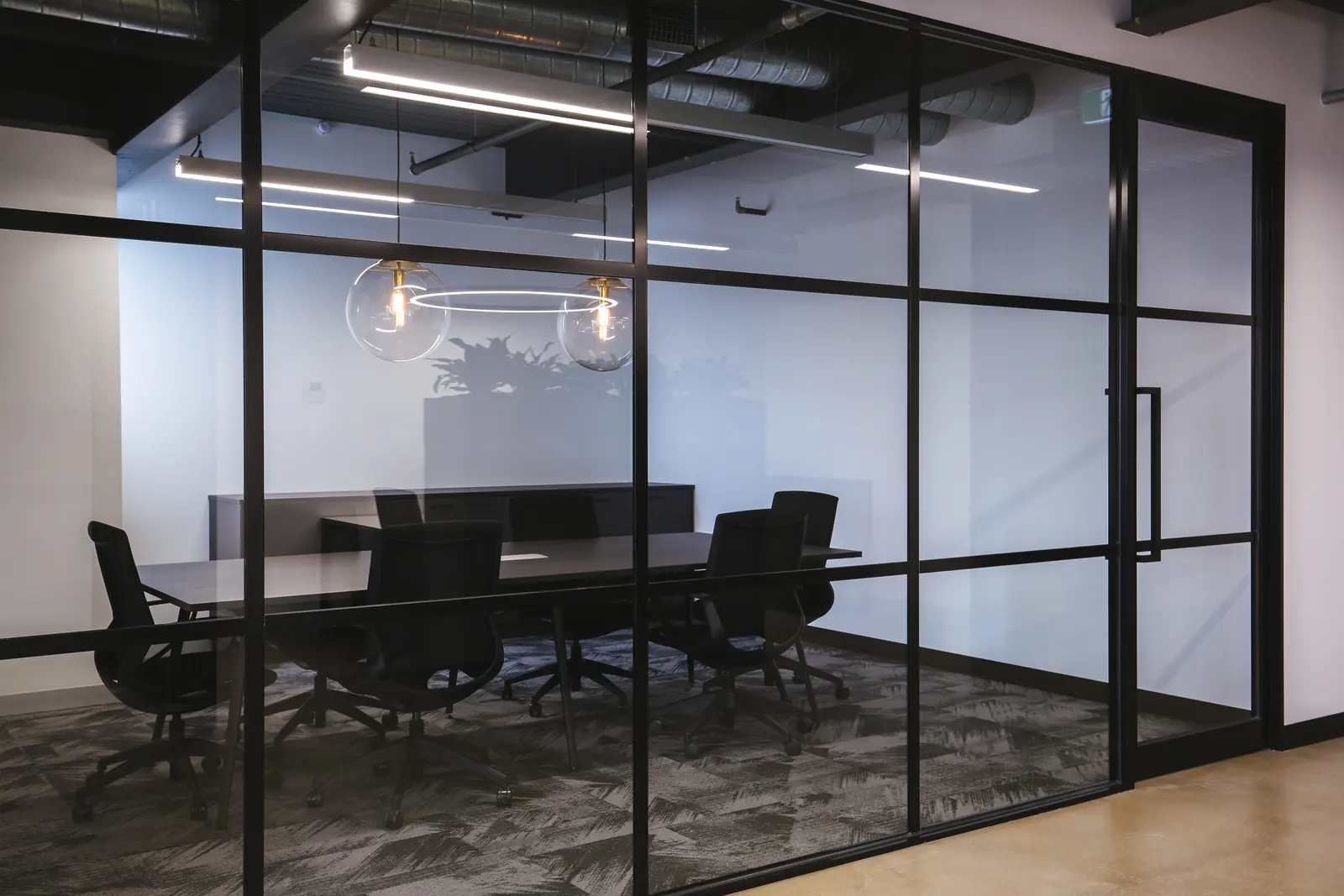 Glass meeting room with black framing and pendant lights