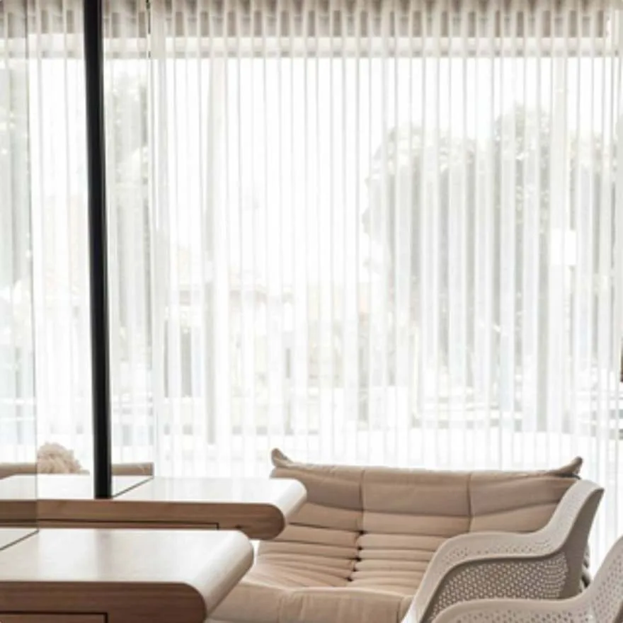 Waiting area with a white lounge chair beside a timber counter and sheer curtains